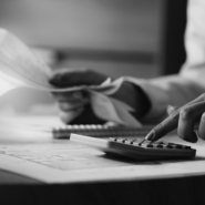 Close-up of economist using calculator while going through bills and taxes in the office.